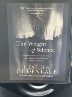 Cover of the novel The Weight of Silence by Heather Gudenkauf, featuring two young girls standing barefoot in dresses, with a dark, shadowy background. The story explores themes of trauma and selective mutism as two families search for missing daughters.